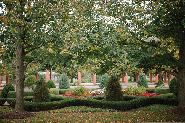 Formal garden with geometric shrubbery and colorful flowers.